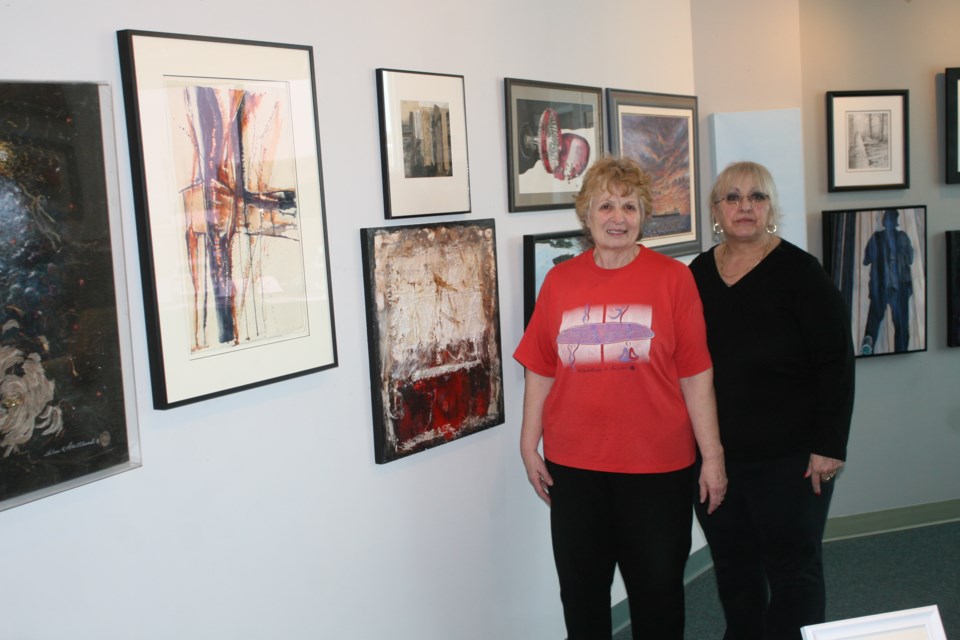 Elliot Lake Art Club members Linda Duke, left, and Lillian Asquith were busy hanging the art pieces in the Northern Ontario Art Association exhibit soon on display at the gallery at the Lester B. Pearson civic centre.  Photo by Kris Svela