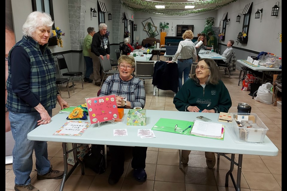 Shirley Wilson, standing, shares news with Horticultural Society greeters Claire Paquette, left, and Charlotte Vlahovich before the meeting begins.