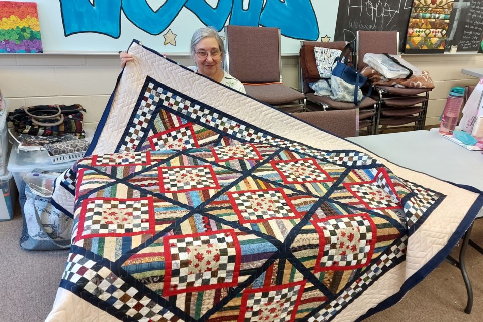 Carmen Perdigao, a quilt guild member for 21 years, holds up the latest Quilt for
Valour.