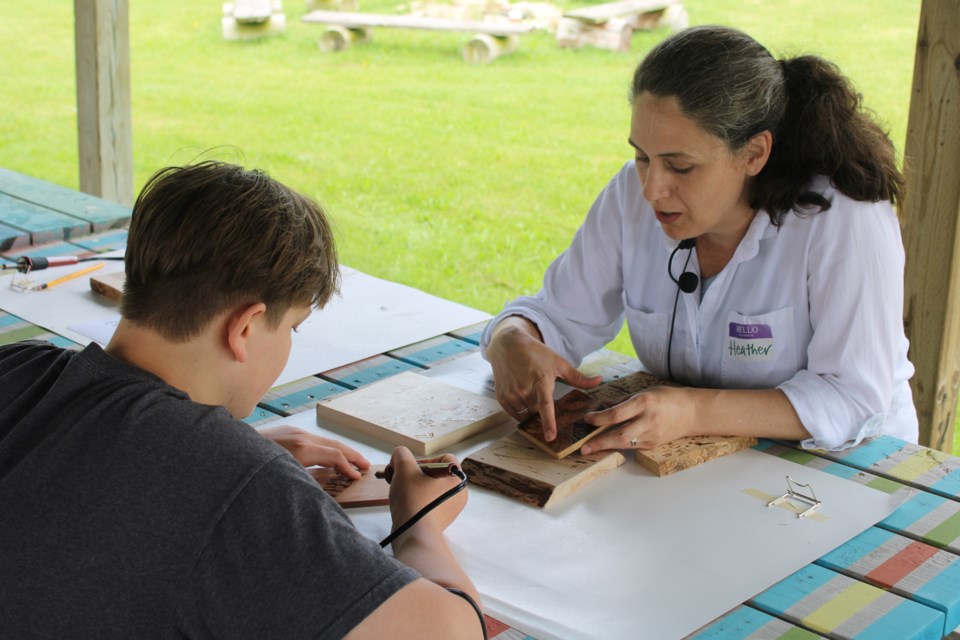 Heather Martin, a pyrographer, talks with a Portage Elora resident about his piece.