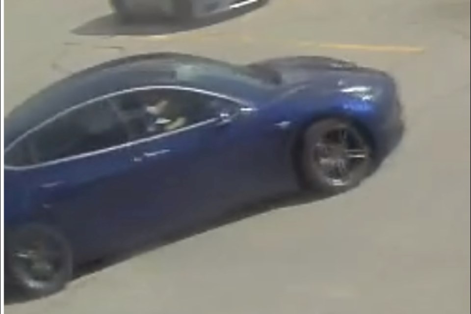 The vehicle is described as a deep blue coloured Tesla (electric) model 3 sedan, with tinted windows and a blue front licence plate