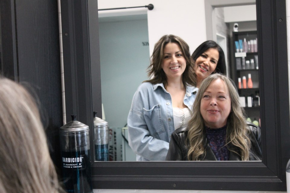 House of Hair Images staff members Kelsey Lewis (left), and Marilyn Mendoza (rear) have fun reflecting on the shop's history with owner Lisa Neddow (seated).