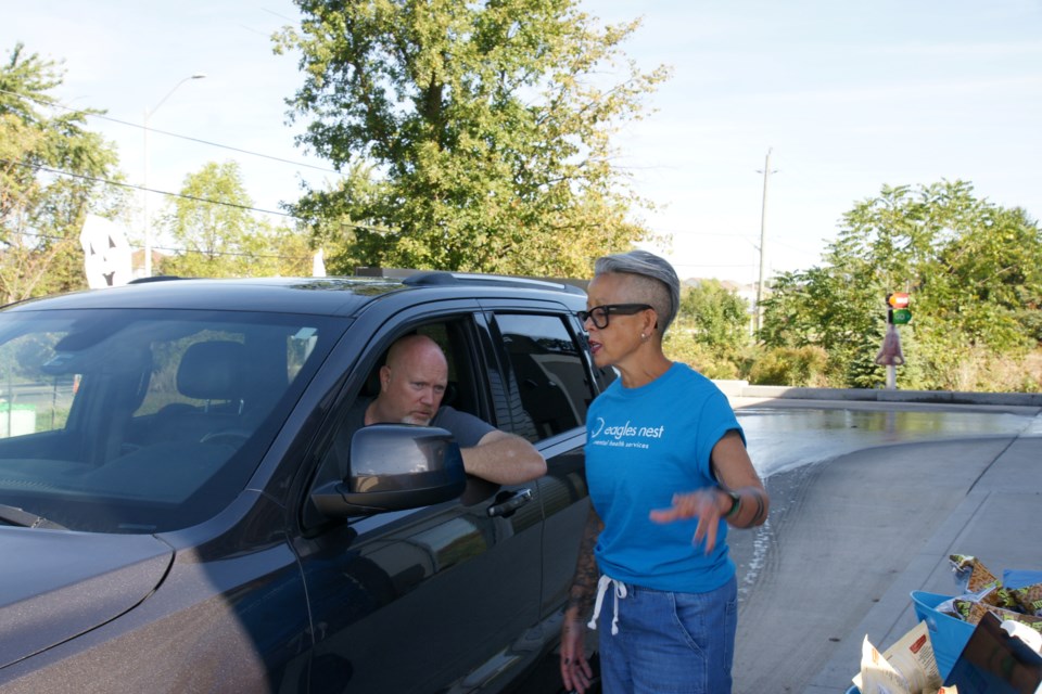 Cary De Vries of Waterdown-gives Dawna Ondrik his order during Eagles Nest's fundraising barbecue at Red Hill Car Wash Saturday. All proceeds from the event, sponsored by Fortinos Waterdown, will help provide mental health supports at low cost to the community. 