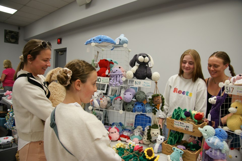 Hanna Hilson checks out the crocheted items at the booth set up by Bryanna Chalmers and Hailey Cloutier in Millgrove Sunday.