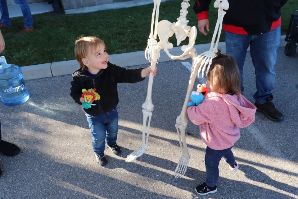 Luca Fernandes and his twin sister, Maya, push a spooky skeleton back and forth at the free pumpkin giveaway. 