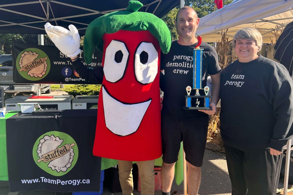 Flamborough Chili Fest mascot Chili Pepper Guy presents Mike and Michelle Schmidt of Stuffed Handcrafted Perogies with this year's People's Choice trophy on Saturday. 