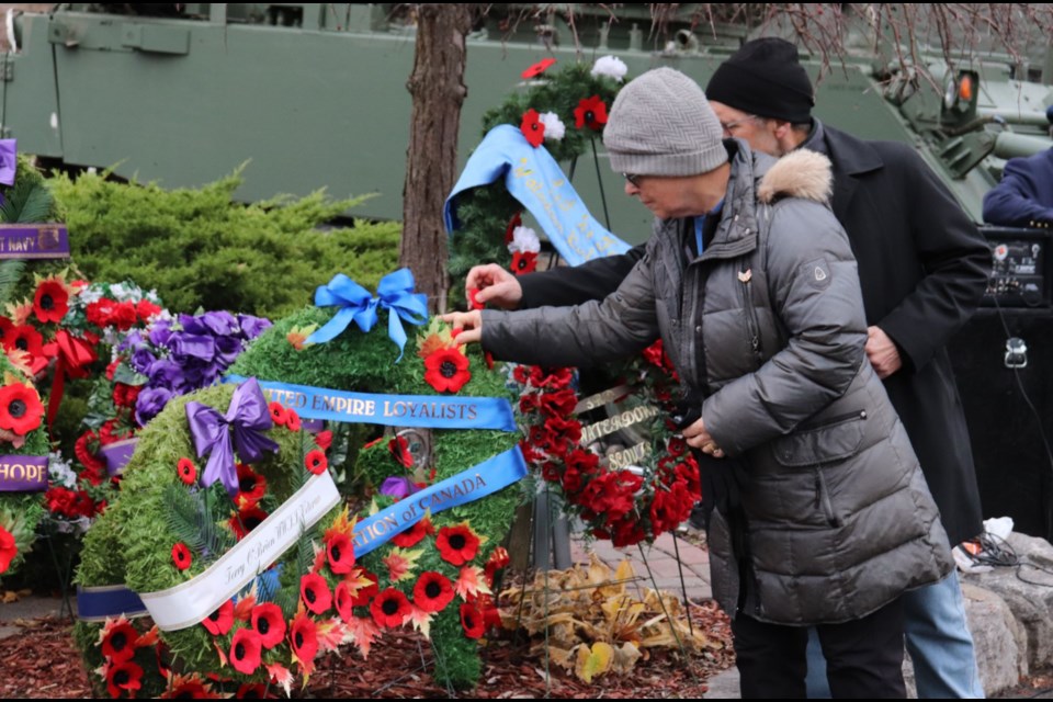 A visitor at the cenotaph puts her poppy on one of the wreaths. 