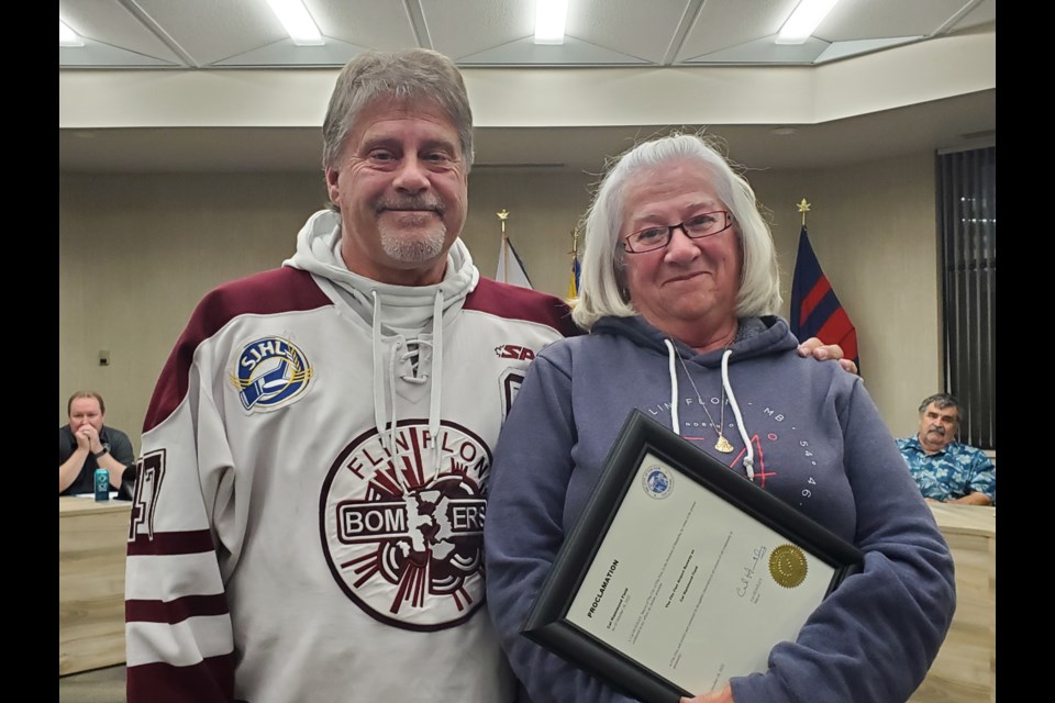 Outgoing Flin Flon mayor Cal Huntley presents Heather Hammond with a signed proclamation renaming part of Flin Flon Airport at the Oct. 15 city council meeting. The airport's runway will be renamed "Cal Hammond Field" after Heather's late husband, a long-time airport employee.