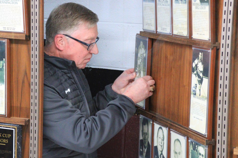 Harvey Bolton slides his own Manitoba Hockey Hall of Fame plaque into its new home at the Whitney Forum's sports hall of fame during a ceremony Dec. 17. Bolton, who has served as a hockey official for over 50 years, was inducted into the hall last fall.