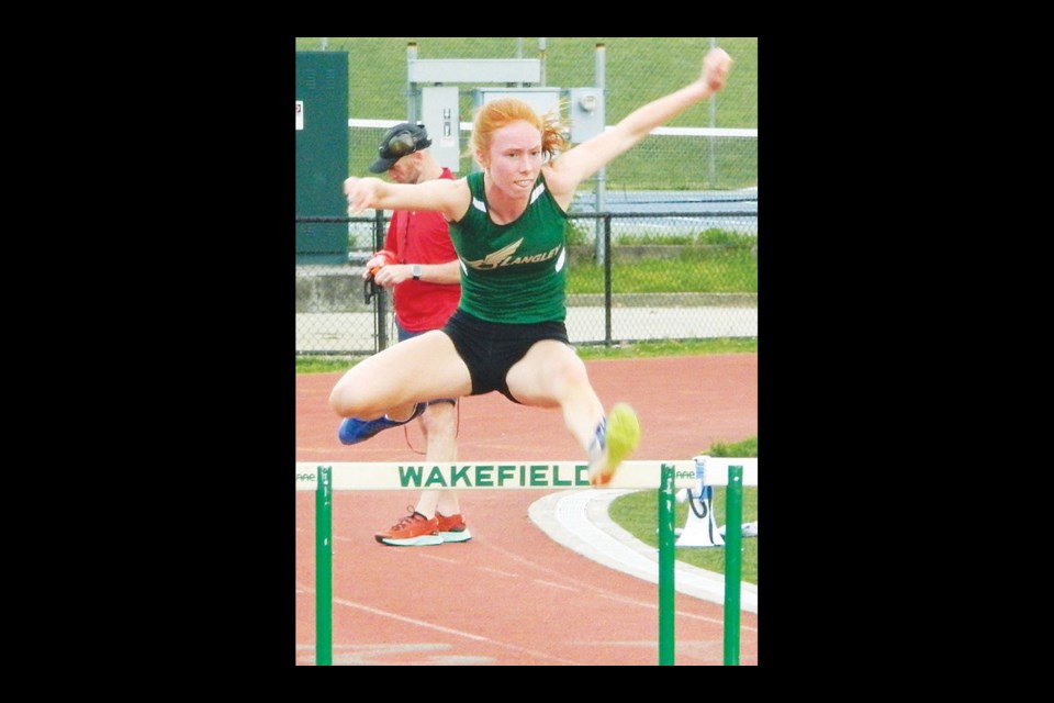 Langley’s Alexandra DeLong clears a hurdle in the 100 district race . [Photo by Dave Facinoli]