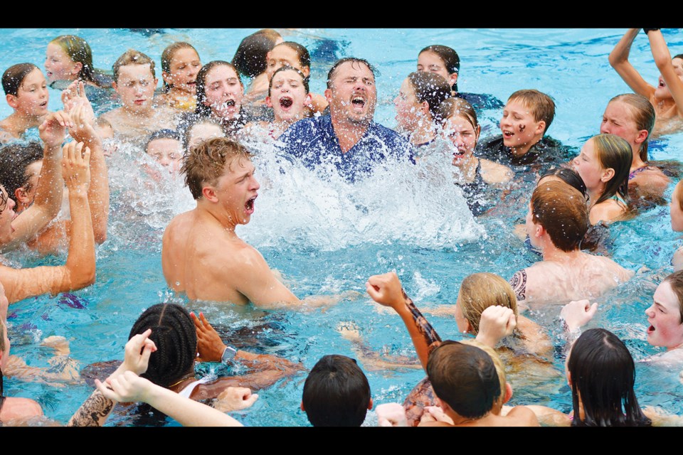 Army Navy swimmers and coaches celebrate in the water after winning the season-ending championship meet.