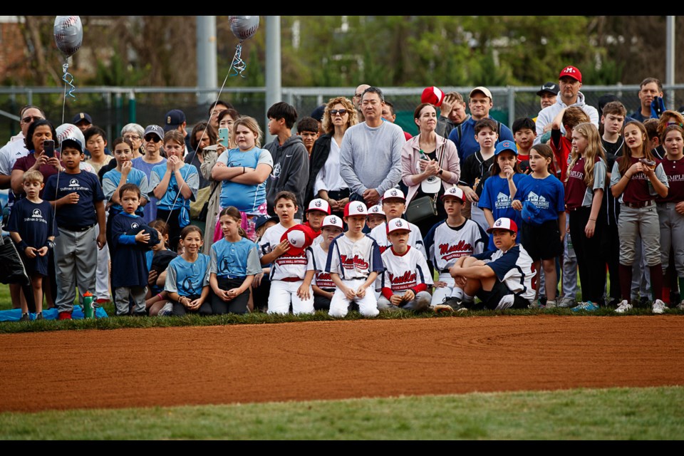 Players and family members watch the opening-day ceremonies.