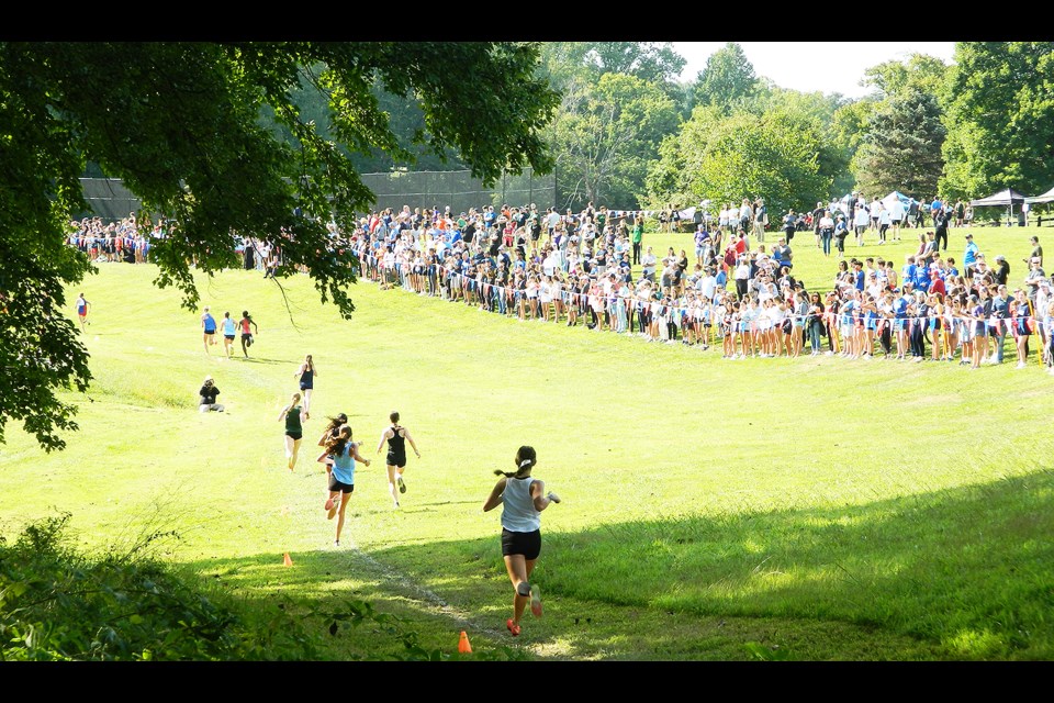 Spectators crowd around the finish area on the course where the runners in the girls varsity race complete the final downhill steps.