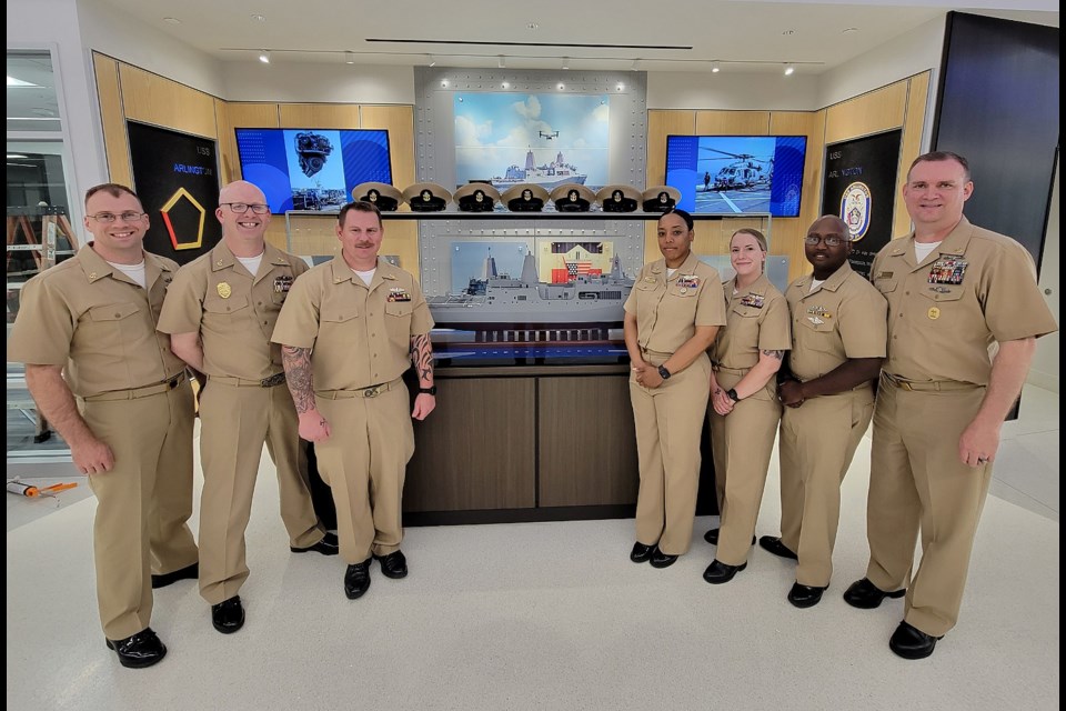 Chiefs from the USS Arlington pose with a scale model of their ship at the Ellen M. Bozman Government Center during a tour in June 2023.