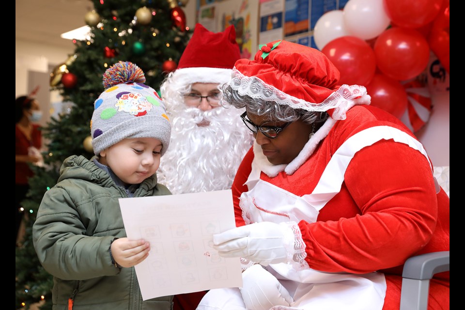 Santa and Mrs. Claus look over a wish list at the VHC Health Pediatrics Center's annual holiday party on Dec. 21, 2023.