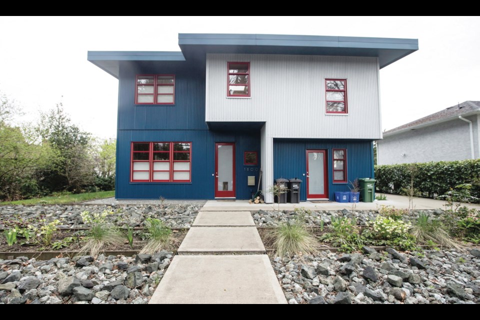 The silver and blue, corrugated steel-sided home was built by Max Huxley and has two living units, with the larger owner’s unit at left. The garden makes a bold statement with a blasted rock “lawn” bisected by a strip of grasses, hellebores and bamboo.