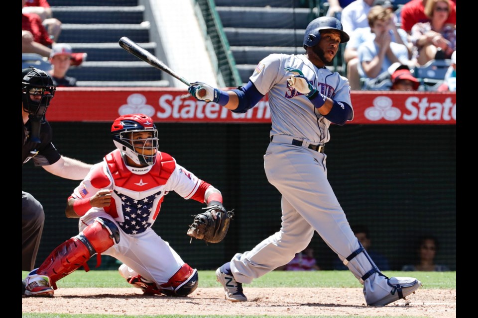 Seattle Mariners' Robinson Cano, right, watches his three-run home run during the eighth inning of Sunday's game against the Los Angeles Angels in Anaheim, Calif.