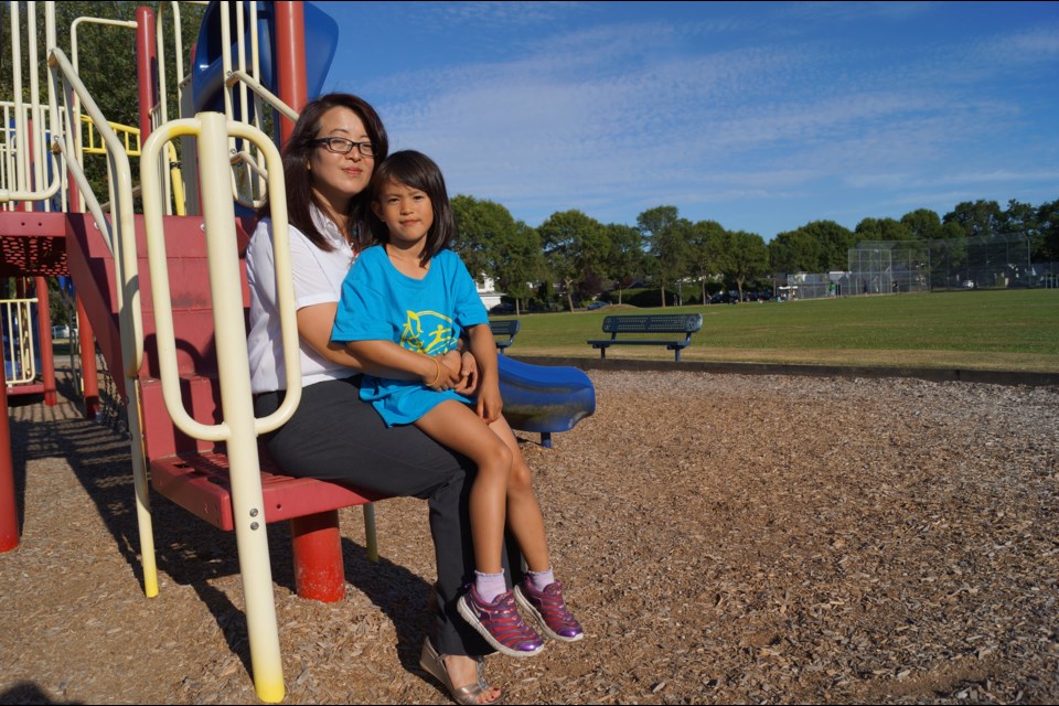 Left, Dawning Zhang with her daughter at Manoah Steves playground, where a model plane nearly hit them Sunday. Below, the hole Zhang says a metal nosecone created when it slammed into the field. Zhang says the model plane pilots are not experienced enough to be flying near playgrounds. Photos by Graeme Wood/Richmond News.