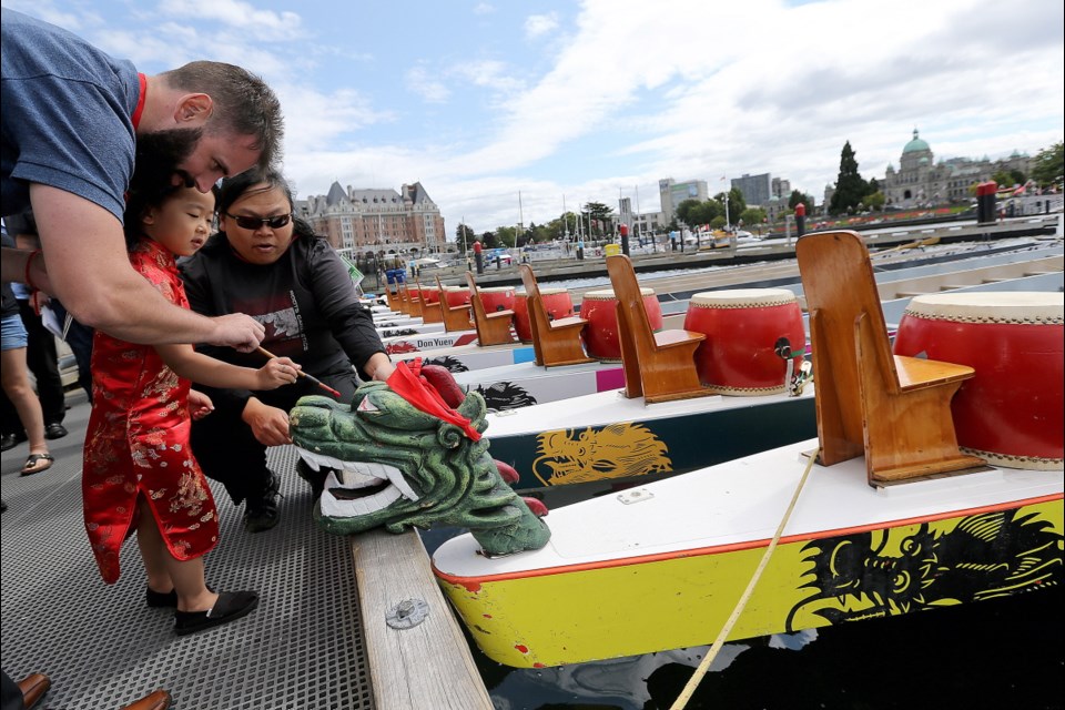 Four-year-old Miyu Loo gets help dotting the eyes from Lee Porter, left, and Jennifer Loo at the ceremonial launch of the 23rd annual Dragon Boat Festival at Ship Point on Friday. Aug. 18, 2017