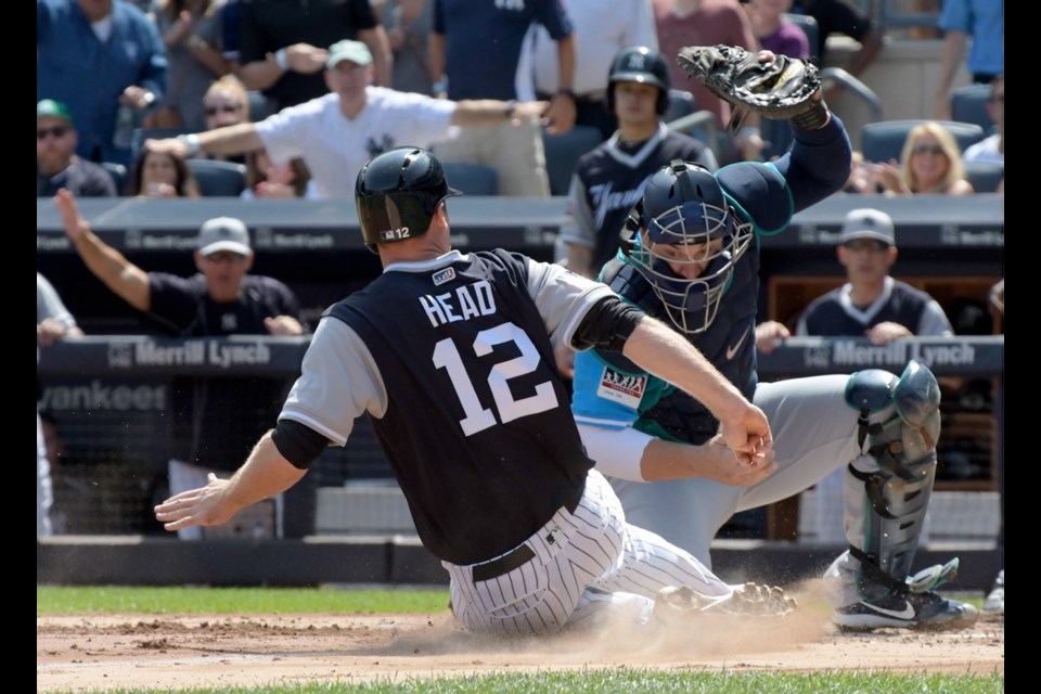 New York Yankees' Chase Headley (12) scores on a three-RBI double by Jacoby Ellsbury as Seattle Mariners catcher Mike Zunino cannot come up with the ball during the first inning of Sunday's game at Yankee Stadium in New York.