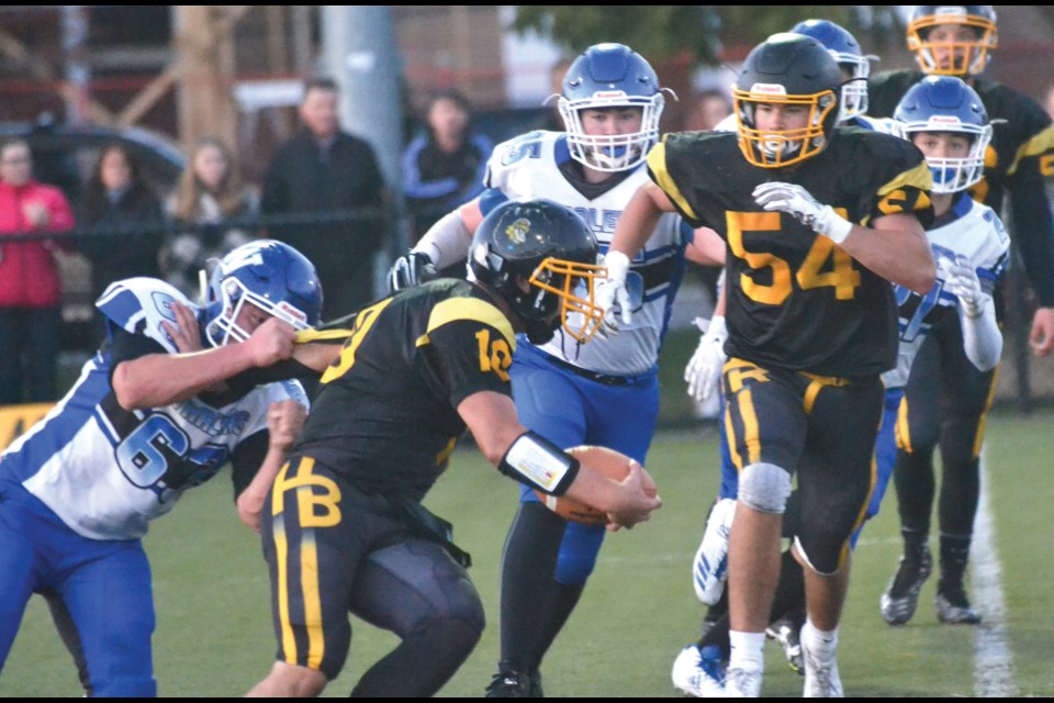 Hugh Boyd quarterback Byron Ruvalcaba tries to escape from the grasp of Ballenas’ Liam Howard during Friday's B.C. High School Football Western “AA” Conference game. Ruvalcaba fired three touchdown passes as the Trojans defeated their Parksville opponents 30-20.