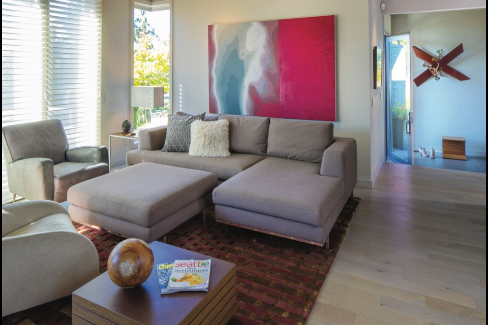 The monochromatic colour scheme in the remodelled living room offers a subtle background palette to let the art and rug pop.