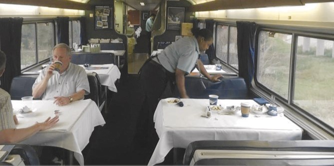 An Amtrak dining car server cleans tables as passengers linger over breakfast on the Sunset Limited, a train that runs between Los Angeles and New Orleans.