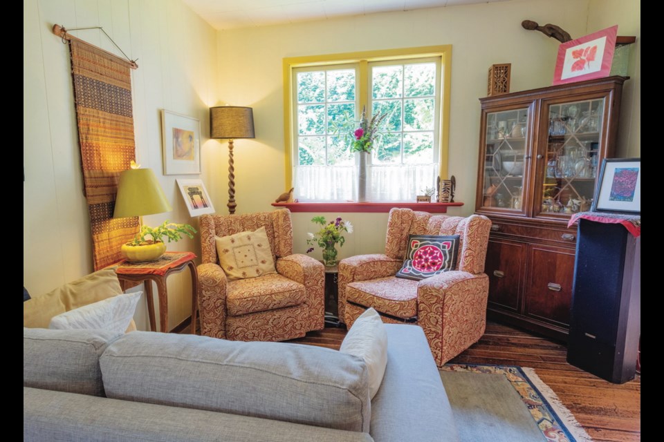 Bev Thompson has filled each room with artwork and unique pieces from her decades of travel to exotic locales. She trimmed the window in a darker shade of yellow and added a red ledge to tie in with the kitchen trim. The glass-fronted cabinet holds glassware.