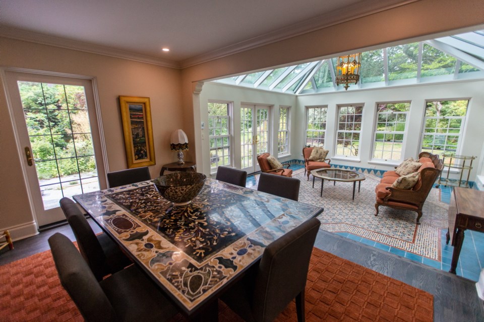 Asian and Indian influences are found throughout the renovated house, reflecting the taste of the homeowners. The dining room with its inlaid mosaic dining table from India looks into the solarium, which features tiles designed by the homeowner with Miranti Moreno, of Toorak Tile in Vancouver.