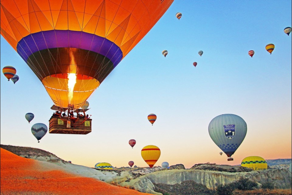 Up, up and away at sunrise in Cappadocia, where hot air balloons drift over a supernatural landscape.