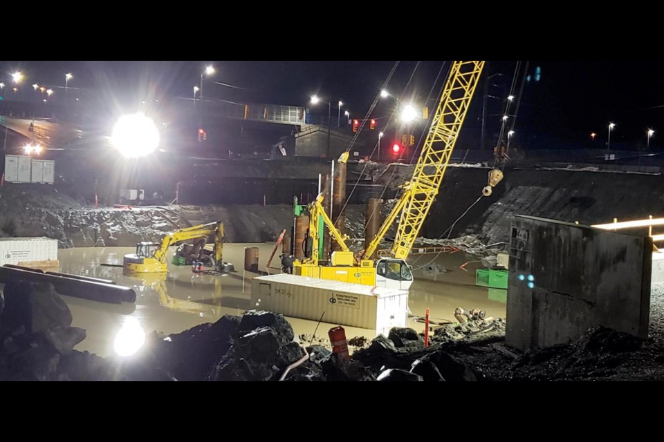 Heavy rains and a malfunctioning pump led to flooding at the McKenzie interchange construction site on the Trans-Canada Highway, leaving some equipment partly submerged.