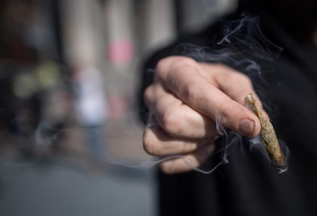 A man holds a joint while smoking marijuana to celebrate the legalization of recreational cannabis,