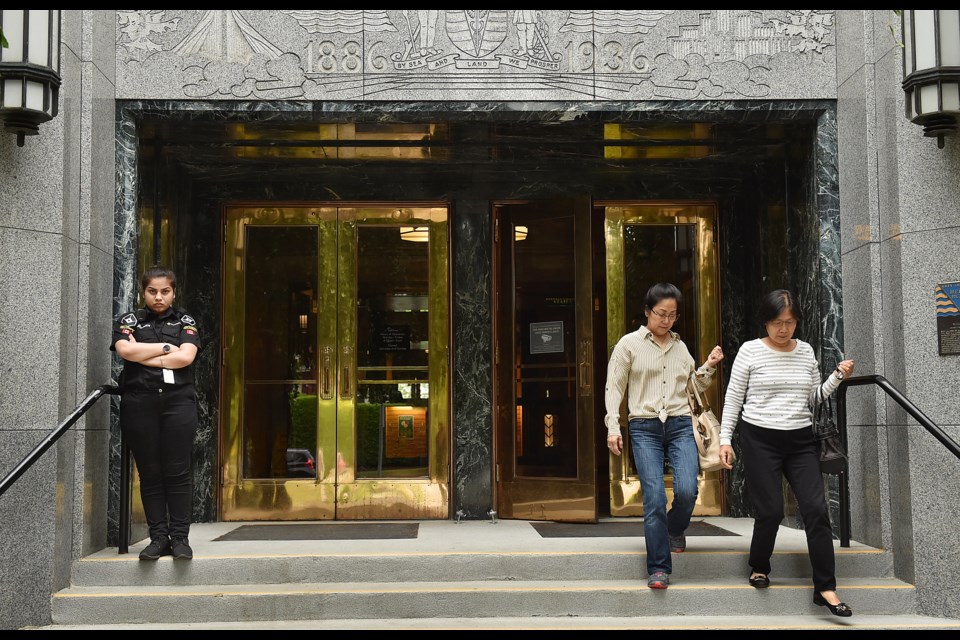 A security guard stands at her post Tuesday outside the main entrance to city hall. Photo Dan Toulgoet