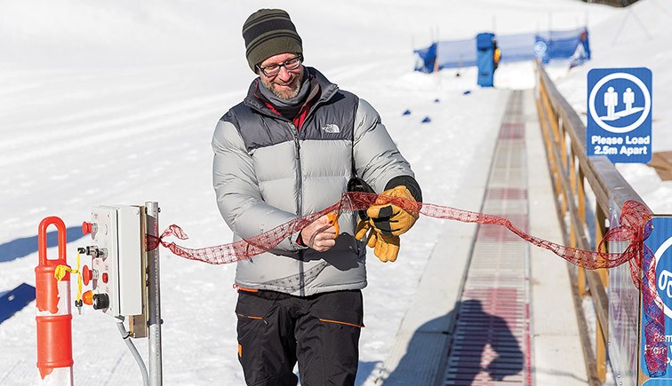 Citizen Photo by James Doyle. Ross Rustad, son of Jim and Noreen Rustad, cuts a ribbon to officially of the Passenger Conveyor Carpet Lift at the Hart Ski Hill on Saturday morning during a ceremony to open the new addition to the Nechako Rotary Learning Centre.