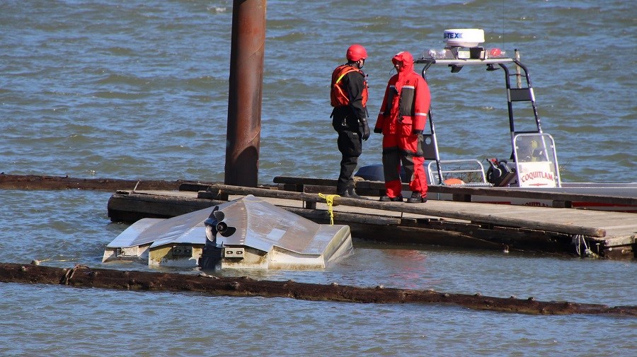 Search and Rescue crews from Coquitlam stand next to a capsized boat on the Pitt River.