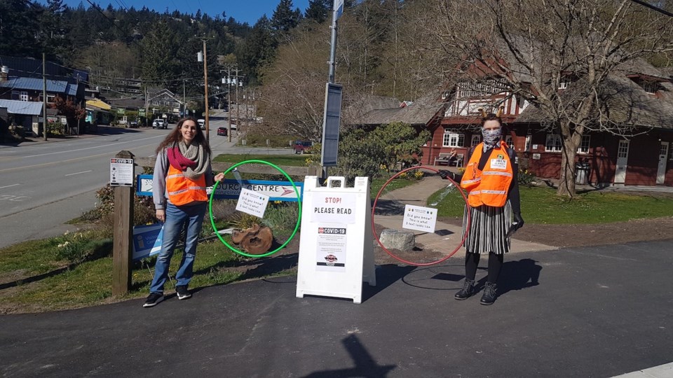 Two people standing with hula hoops between them in front of the library