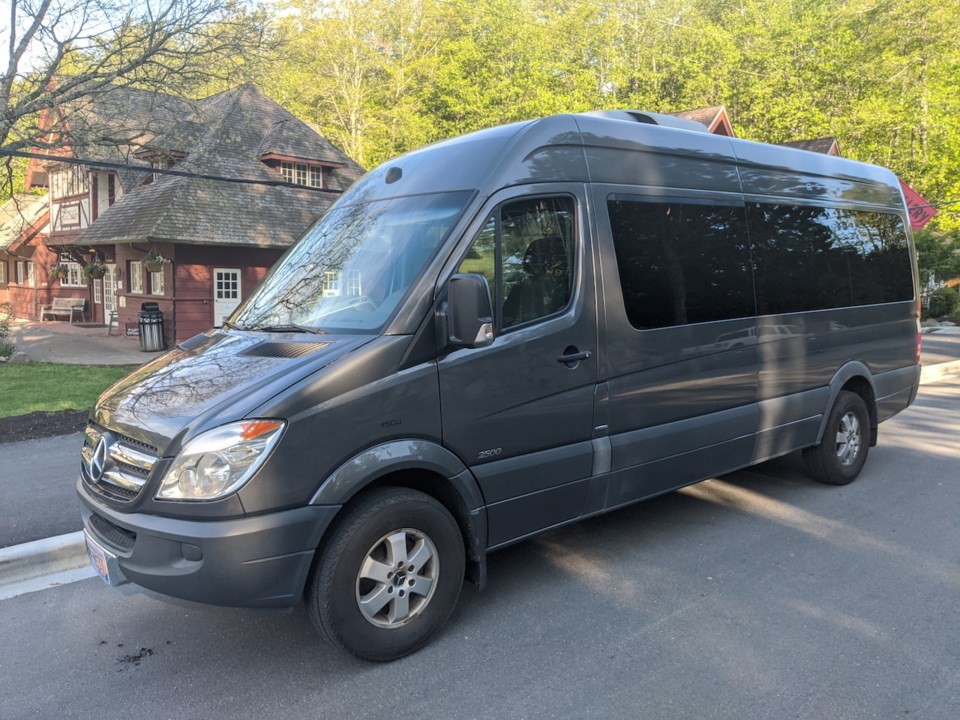 A small grey bus in front of the library