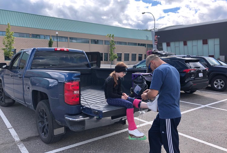 Troy Sieben helps his daughter Mariah, nine, get ready for her figure skating lesson on Tuesday, outside the Kin Centre arena. Under new public health rules, skaters are required to get themselves ready before entering the building.