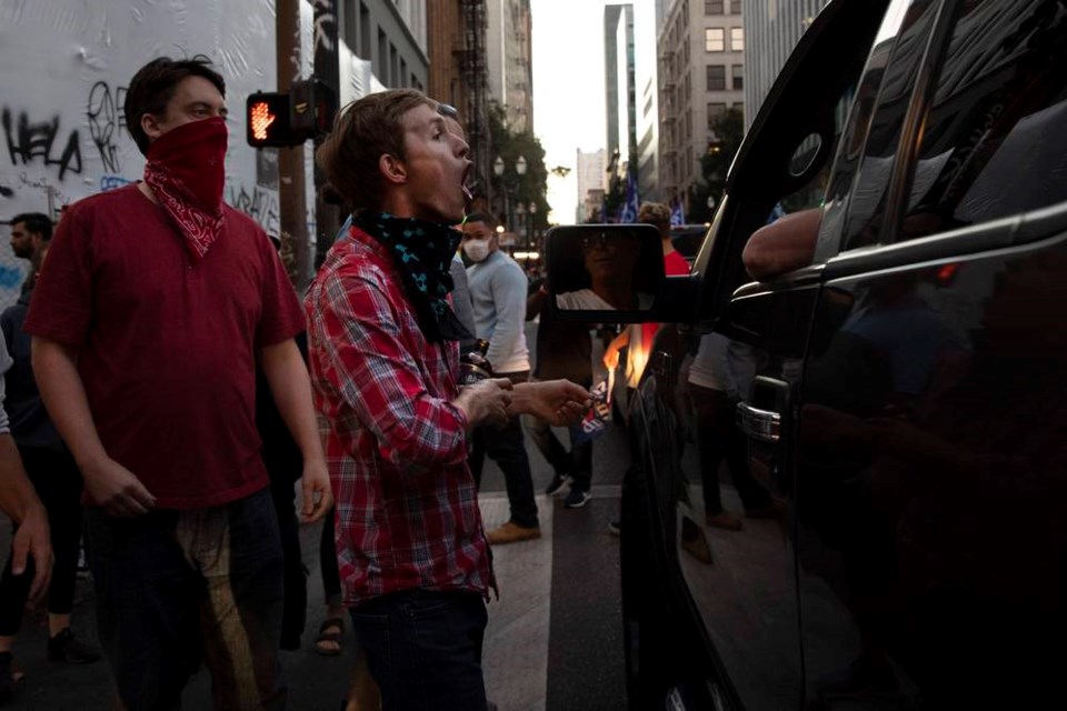 A Black Lives Matter protester yells at a supporter of President Donald Trump during a rally and car parade Saturday, Aug. 29, 2020, in Portland, Oregon. One person was shot and killed late Saturday in Portland as a large caravan of President Donald Trump supporters and Black Lives Matter protesters clashed in the streets, police said. It wasn’t clear if the shooting was linked to fights that broke out as a caravan of about 600 vehicles was confronted by protesters in the city’s downtown. (AP Photo/Paula Bronstein)