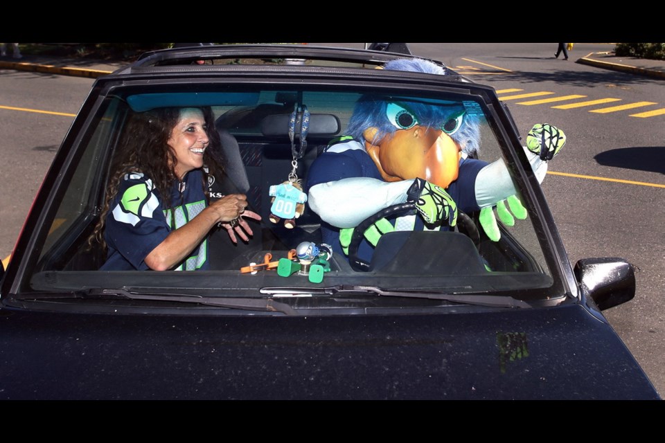 Seattle Seahawks fan Sharon White lets team mascot Blitz take the wheel of her car during a promotional event for Island fans of the NFL franchise. White shows her allegiance with her licence plate, at right. Hundreds of fans showed up at Jersey City in Mayfair Shopping Centre and later the Sticky Wicket in the Strathcona Hotel.