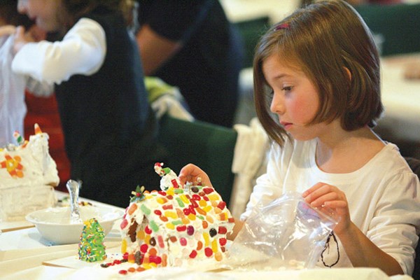 Holiday baking: Annalies Smigel decorates her house at the annual gingerbread event organized by Doreen Hammond. Hammond, 76, makes 200 gingerbread houses each year for children and families to decorate at St. Alban's Church.