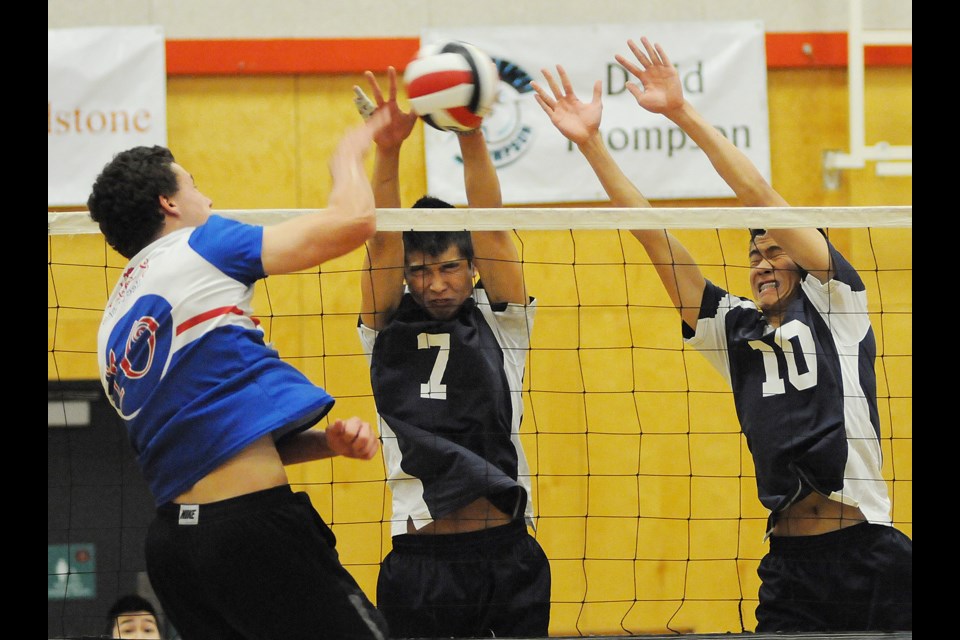 John Oliver's Mark Penner (No. 10) nails the ball at David Thompson blockers Kalvin Liang (No. 7) and Brandon Lam (No. 10) in a senior boys volleyball quarter-final Oct. 28 at Magee.