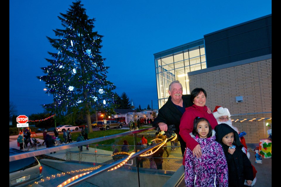 Mayor Derek Corrigan poses with Chesny and EJ Cayabyab with their mom Hazel after the Christmas tree outside the Edmonds Community Centre was list on Nov. 23.