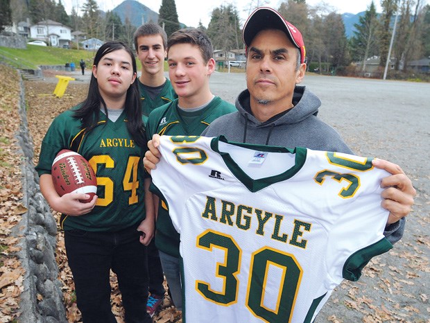 Teammates Troy Martell (left), Cole Theobald, Jackson Washington and head coach Wayne Theobald of the Argyle junior football team pay tribute to the No. 30 jersey of teammate Marcos Borboa Lara who died last summer in an accident at Indian Arm's Granite Falls.