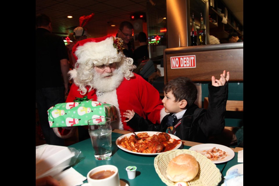 Santa spotted: Santa gives a gift to Anthony Naffaa at the annual Christmas Eve party held at Anton’s Pasta Bar. Nearly 600 people in need, including Burnaby families and people from Vancouver’s Downtown Eastside, attended this year.