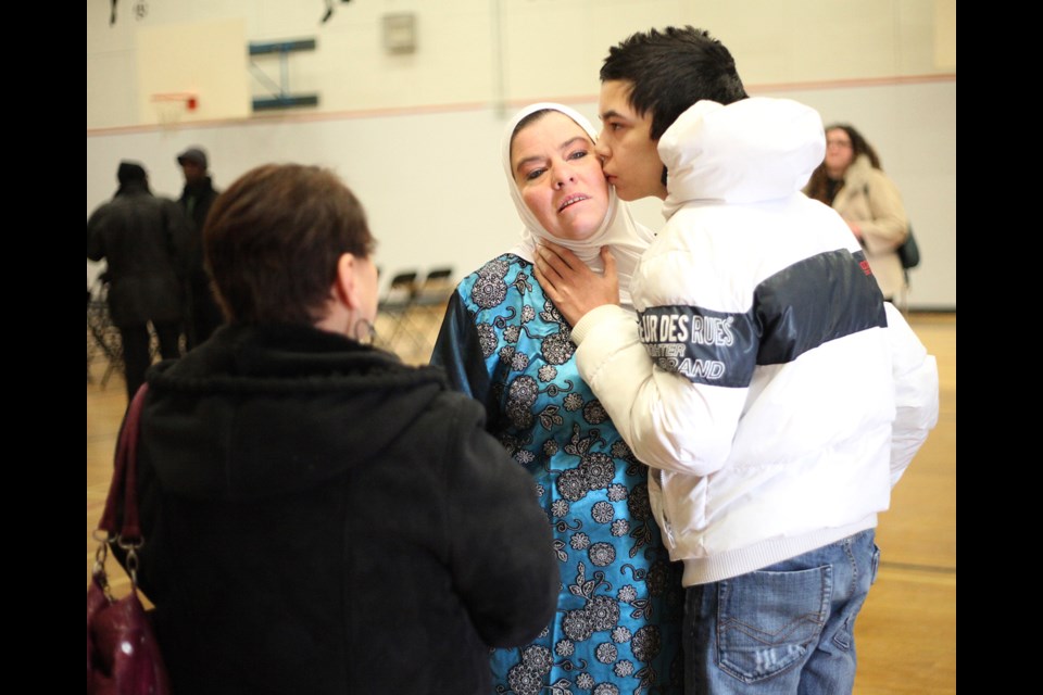 Karim Meskine's mother Julie, gets a kiss from her other son at the memorial at John Robson Elementary School.