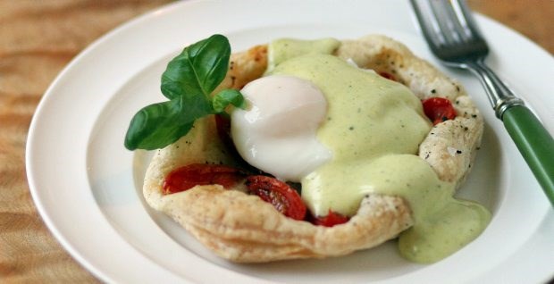 A poached egg on a cherry tomato tart is accented with pesto hollandaise. The puff pastry is sold frozen at most supermarkets.