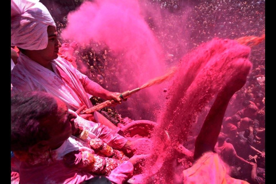 An Indian saint sprays coloured water as another throws coloured powder on devotees during Holi festival celebrations at the Swaminarayan Hindu temple in Ahmadabad, India, on Monday. The holiday, celebrated mainly in India and Nepal, marks the beginning of spring and the triumph of good over evil.