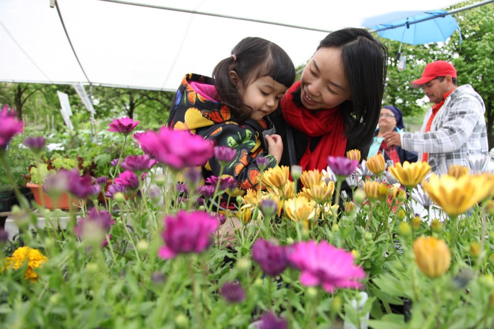 Mya Gill and Miyuki Moizumi take time to smell the flowers at the farmers' market at Burnaby City Hall.