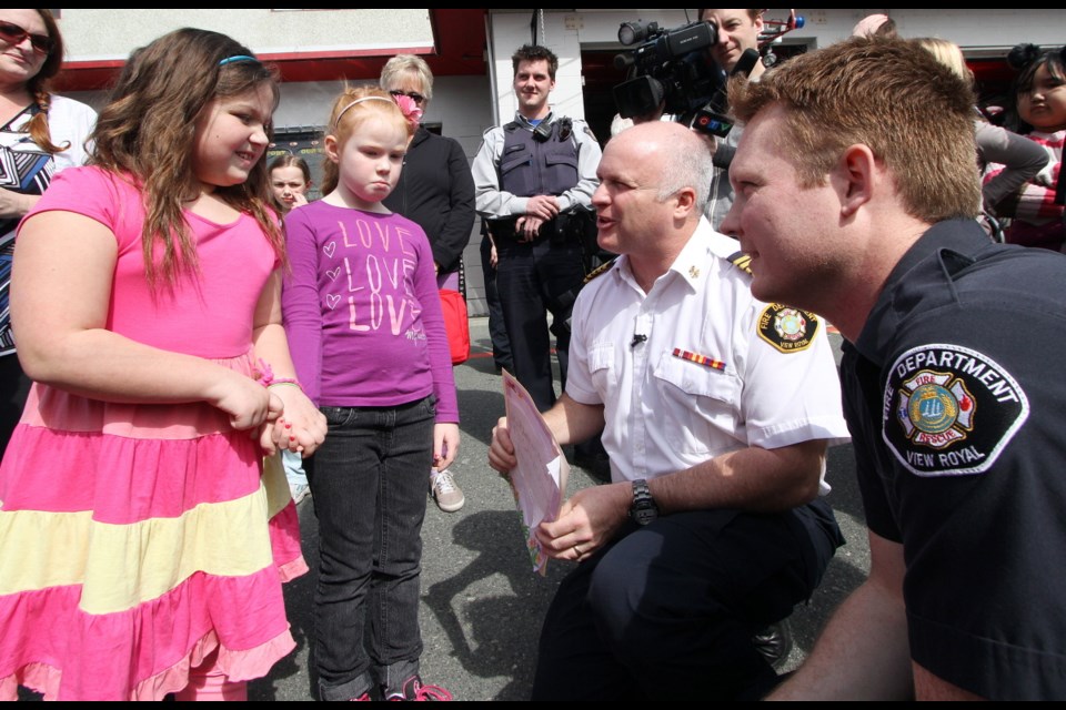 Wednesday: Firefighter Dave Sheriff and View Royal Fire Chief Paul Hurst talk to Katrina Vanwinkle, 9, as the students from View Royal Elementary walked to the View Royal Fire Hall to thank those involved in the rescue of Katrina from a house fire.